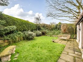 A garden with grass and a wooden bench at Converted Stone Barn -20 Acres - Farm Animals! in Corwen