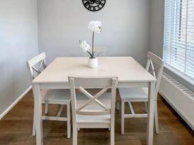 A dining table with chairs and a clock at 2 Bed House - Sleeps 4 - Garden - Parking - Wifi, Kendal