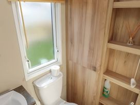 A bathroom with a toilet and a shelf at CaravanSleeps6-FreeParking-QuietRetreat-Nature in Paignton
