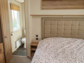 A bedroom with a bed and a bathroom doorway at CaravanSleeps6-FreeParking-QuietRetreat-Nature, Paignton