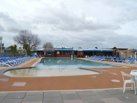An outdoor pool area with sun loungers and a building at 293 Static caravan Beverley Bay Paignton