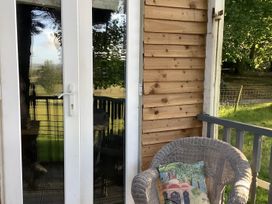 Double doors leading to an outdoor area with a chair and cushion at Dobbin the horse box in The Lake District, Cockermouth
