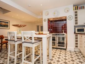 A kitchen with bar stools and kitchen appliances at Rhiwlas in Rhosneigr