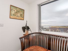 A sitting room with a bench, map on the wall, and window at Rhiwlas in Rhosneigr