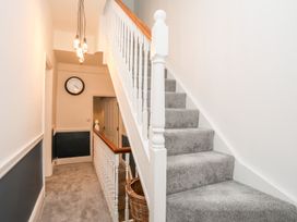 A staircase and hallway with grey carpet at Rhiwlas in Rhosneigr