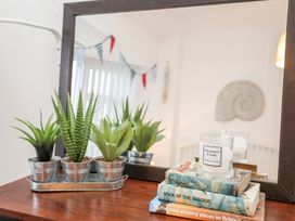 A table with a mirror, potted plants, a candle, and books at Rhiwlas Rhosneigr