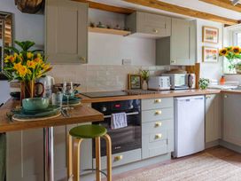 A kitchen equipped with oven, dishwasher, and table at Cotswolds Cozy Cottage Retreat - pet friendly, Finstock