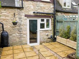 A garden with a stone wall and paving stones at Cotswolds Cozy Cottage Retreat - pet friendly, Finstock