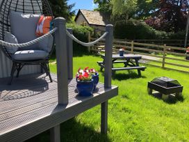 A garden with a hanging chair and picnic table at The Shepherds Hut at Hafoty Boeth Corwen