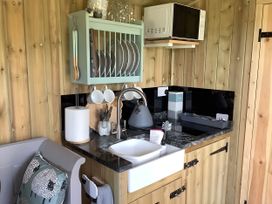 A kitchen with sink, microwave, and utensils at The Shepherds Hut at Hafoty Boeth Corwen