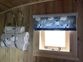 A bathroom with towels on a rack and a window with a roller blind at The Shepherds Hut at Hafoty Boeth in Corwen