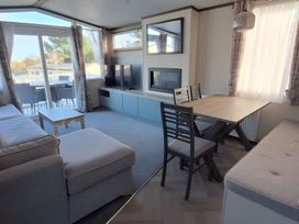 A living room with a sofa, coffee table, and dining table at Tranquil Lodge Retreat in Paignton