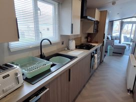 A kitchen with sink, appliances, and cabinets at Tranquil Lodge Retreat in Paignton