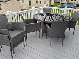 A table and chairs on the patio at Tranquil Lodge Retreat in Paignton