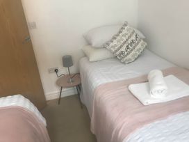 A bedroom with two single beds and a bedside table with lamp at 2-Bed Apartment Sleeps 4 with Garden
