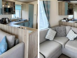 A kitchen area with microwave and sink and a living area with sofa at Beautiful Static Caravan Hoburne Devon Bay