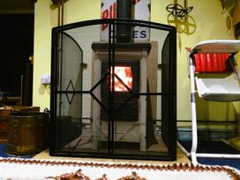 A wood stove behind a screen in a living room with a rug at Family Country Cottage with a private Valley View