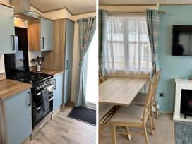A kitchen with cabinets and a stove, and a dining area with a table and chairs at Static Caravan Hoburne Devon Bay