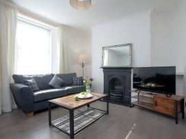 A living room with a sofa, coffee table, television, and lamp at Torquay - House - Sleeps 6 - Pet Friendly