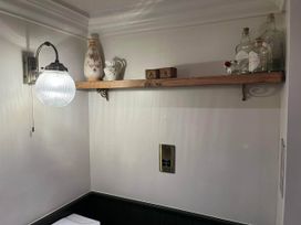 A shelf with decorative items and a light in a bathroom at Quiet cottage on the rural edge of Brixham