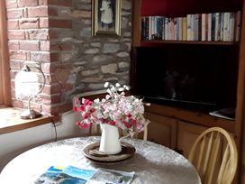 A dining room with a table, chairs, and a television at Quiet cottage on the rural edge of Brixham
