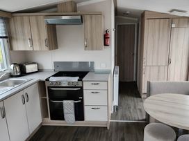 A kitchen with cabinets, stove, sink, kettle, and table at Beverley bay 2-Bed Caravan, Sleeps 6, Pet Friendly 