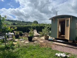 A garden with a hut, seating area, and planters at Shepherd Hut Gloucester