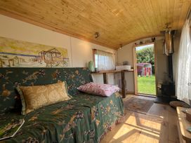 A living room with a sofa and table in the Shepherd Hut in Gloucester