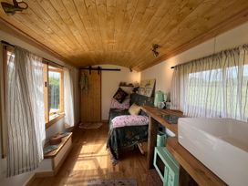 A living room with a sofa and kitchenette at Shepherd Hut in Gloucester