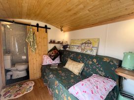 A living room with a sofa and a bathroom door at Shepherd Hut in Gloucester