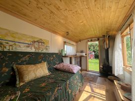 A living room with a sofa and a door leading outside at Shepherd Hut in Gloucester