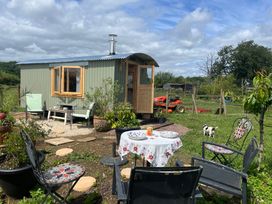 An outdoor area with a shepherd hut and table with chairs at Shepherd Hut in Gloucester
