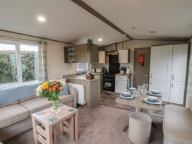A living room with a sofa and kitchen area at Pepper Pot Lodge in Knaresborough