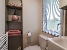 A bathroom with a sink, toilet, and shelf at Pepper Pot Lodge in Knaresborough