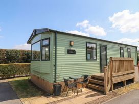 A mobile home with a wooden deck and seating area at Pepper Pot Lodge in Knaresborough