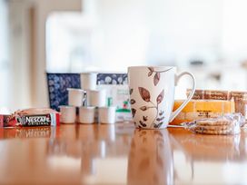 A dining table with a coffee mug and snacks at Luxury 2 Bed Room Lake View Apt Bowness Parking in Bowness-On-Windermere