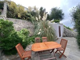 A garden with a wooden table and chairs surrounded by plants at 4 Bed House-Sleeps 8-Parking-Pets-MarinaSeaView in Torquay