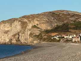 A beach with a rock formation and houses in the background at Sea View, East Parade Llandudno