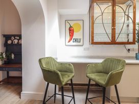 A kitchen with green chairs and wall art at Sea View, East Parade in Llandudno