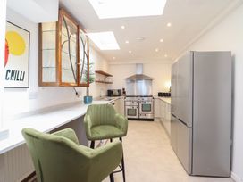 A kitchen with a refrigerator, oven, sink, and bar stools at Sea View, East Parade Llandudno