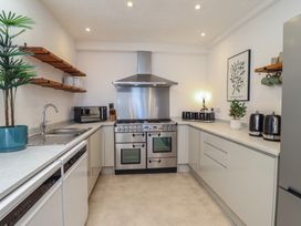 A kitchen with stove, sink, and microwave at Sea View, East Parade in Llandudno
