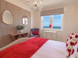 A bedroom with a bed and windows at Sea View, East Parade in Llandudno