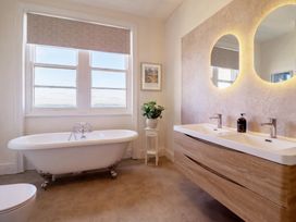 A bathroom with a bathtub and dual sinks at Sea View, East Parade Llandudno