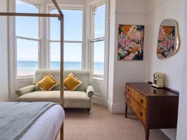 A bedroom with a sofa, dresser, and window view at Sea View, East Parade in Llandudno