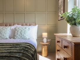 A bedroom with a bed, side table, drawer unit and a plant at Sea View, East Parade, Llandudno