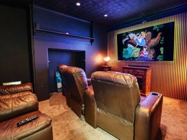 A home theater with recliner chairs and a television at Sea View, East Parade, Llandudno