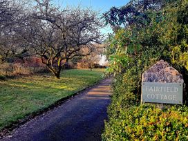 A pathway alongside trees and a sign for Fairfield Cottage