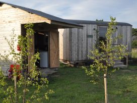 Two wooden structures with doors in a grassy area at Restored circus wagon Saltburn-By-The-Sea