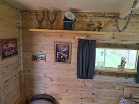 A corner with a shelf, cups, frames, and a window at Restored circus wagon Saltburn-By-The-Sea