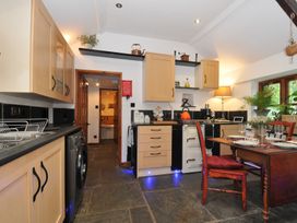 A kitchen with cabinets, a table and chair at Coach House in Camelford